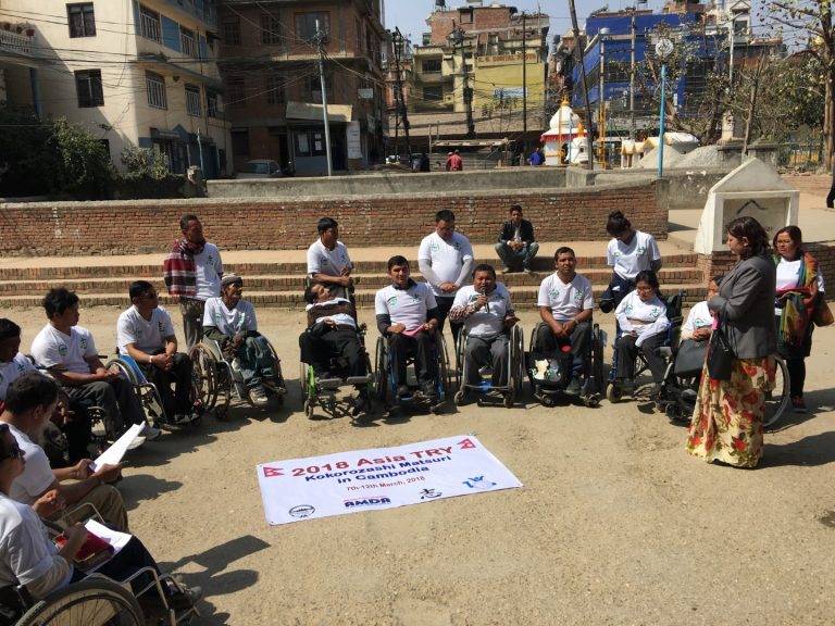 person using wheelchair are sitting in a round circle and a person is speaking on microphone
