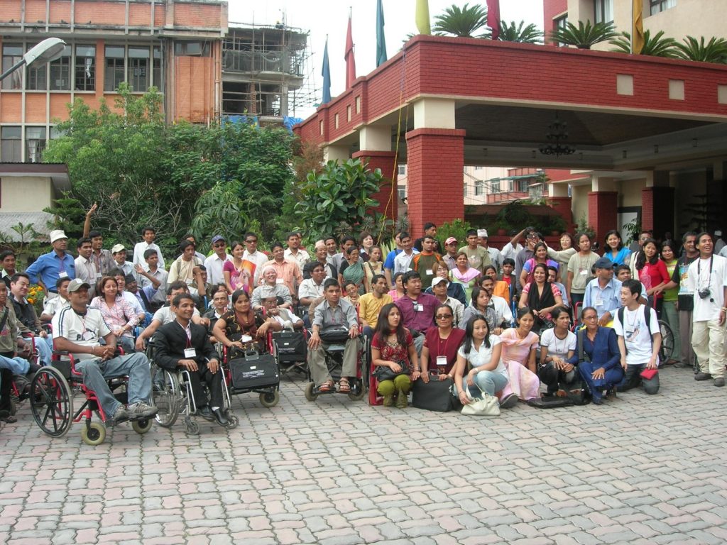 a large group of people are posing for photo graphcs. In the front row there are persons using wheelchair